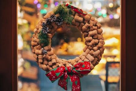 Creative christmas wreath of wine corks, pine cones and red bow on door